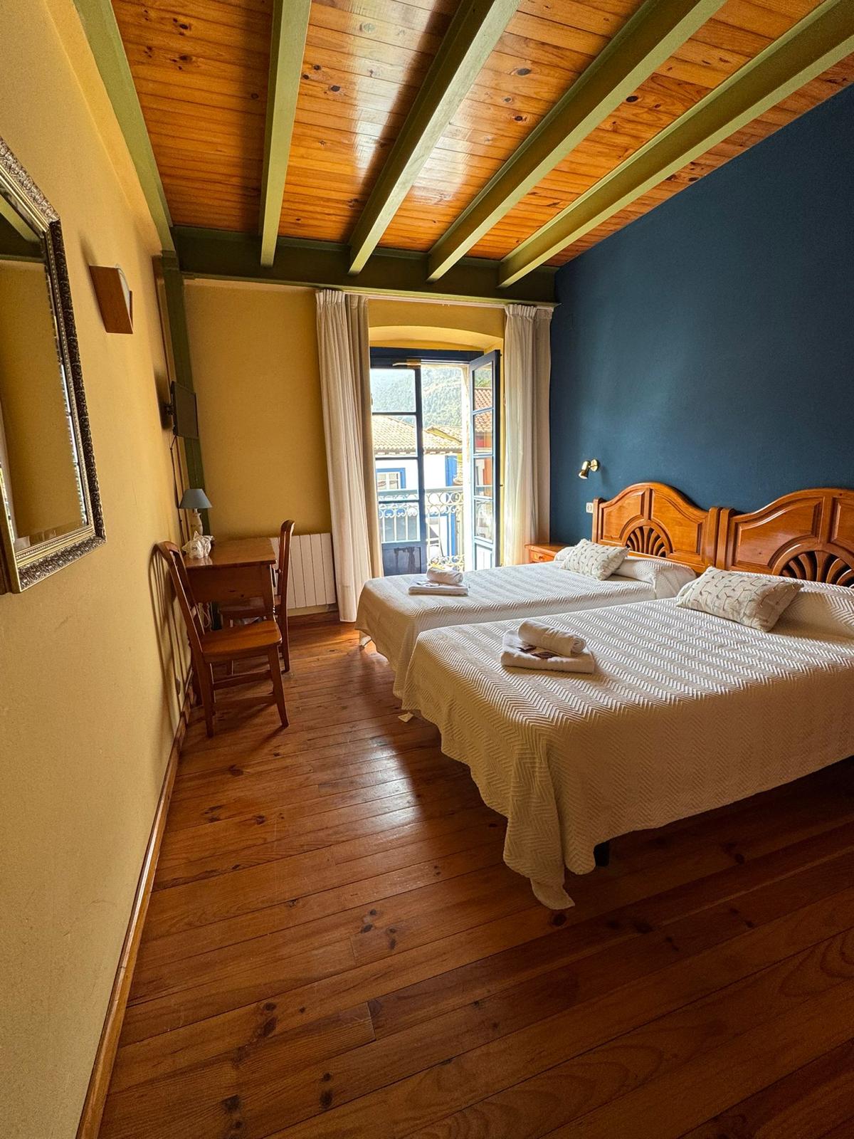 Habitación doble superior Hotel Cuevas del Mar Nueva de Llanes con pared azul y ventana balconera
