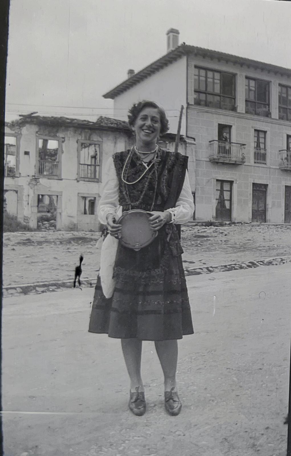 Fotografía histórica en blanco y negro de vecina de Nueva de Llanes con traje tradicional aldeana asturiana y pandereta ante el Hotel Cuevas del Mar en sus primeros años
